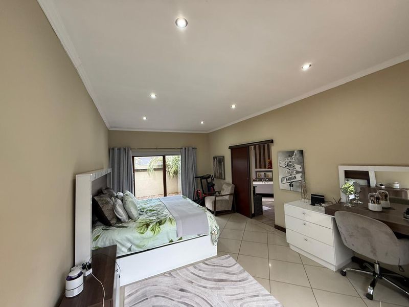 Spacious bedroom featuring tiled flooring, recessed downlighting, and a sliding door providing access to an outdoor area.
