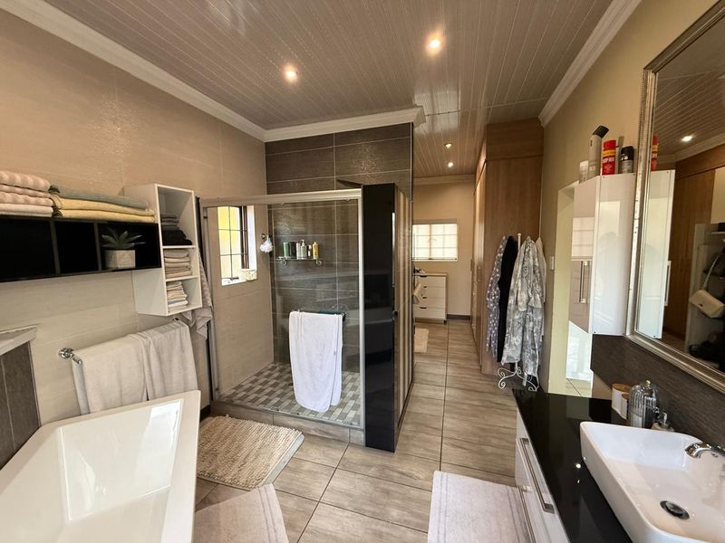 Modern bathroom featuring a glass-enclosed shower, a freestanding bathtub, a vanity with a black countertop, and tiled flooring.