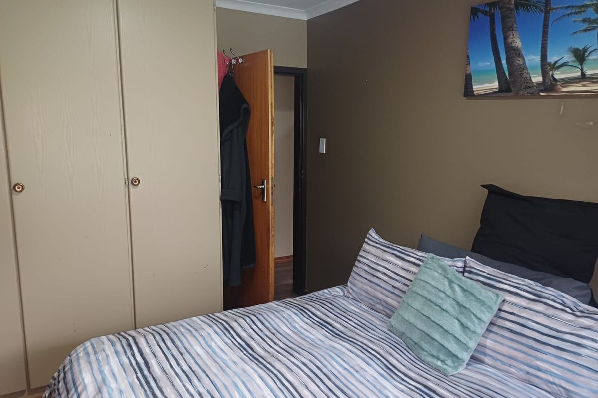 A functional bedroom featuring built-in cupboards and neutral wall tones, providing a practical living space.