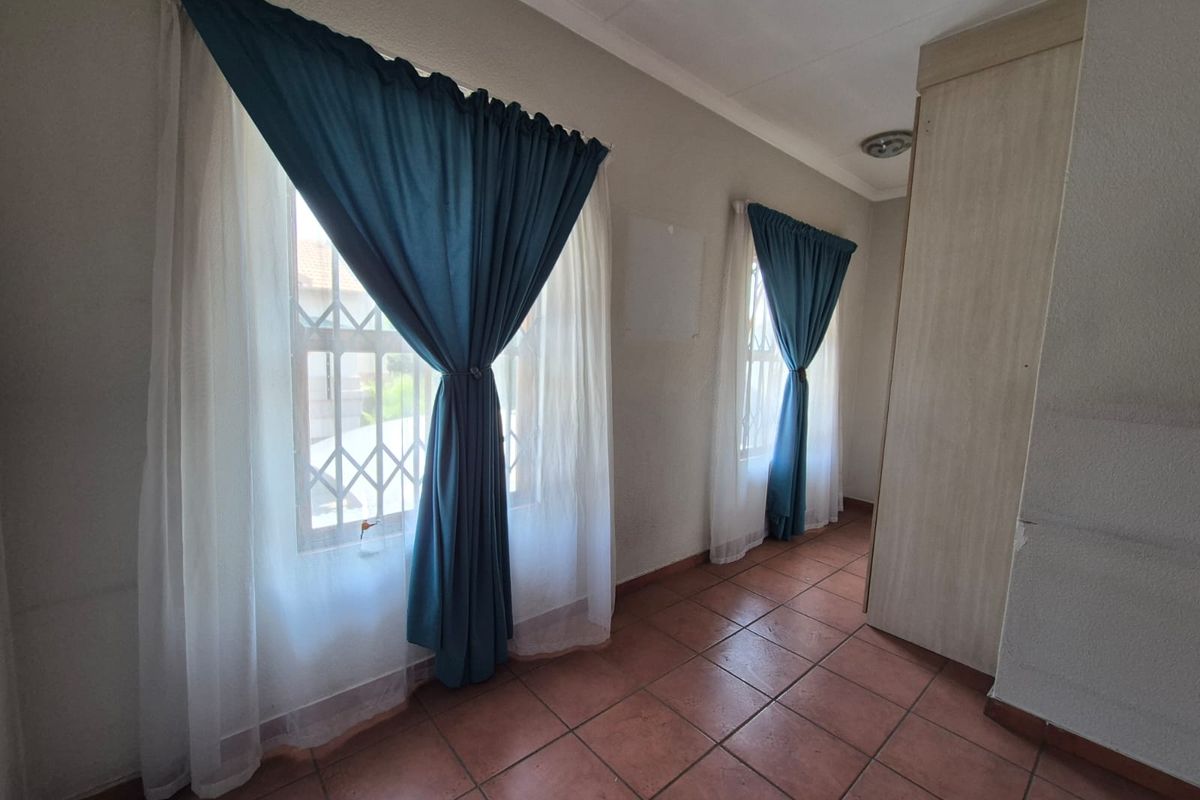 A bedroom featuring tiled flooring, built-in cupboards, and security bars on the windows.