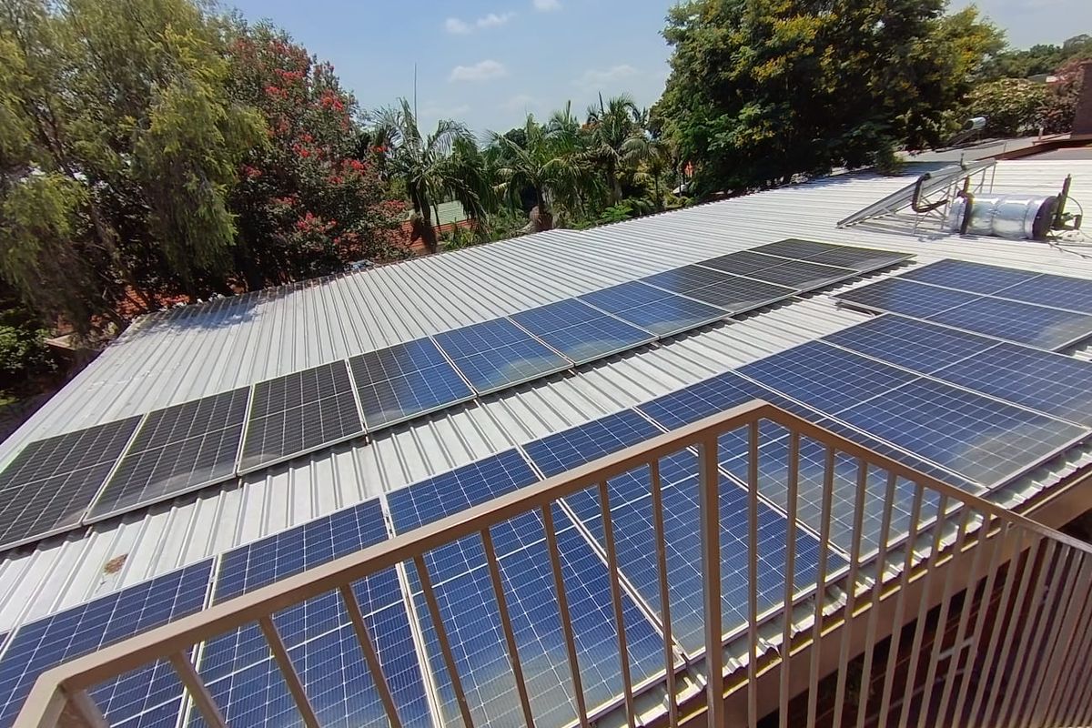 Elevated view of a metal roof featuring a large array of solar panels and a solar water heating system.