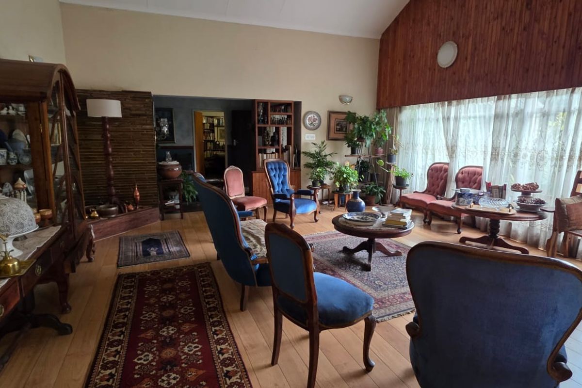 Spacious living room featuring high vaulted ceilings, timber wall paneling, and large windows allowing for ample natural light.