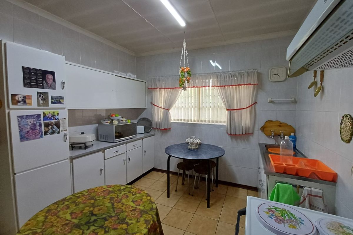 A functional kitchen featuring white cabinetry, tiled walls, and a dedicated breakfast nook area with natural light.