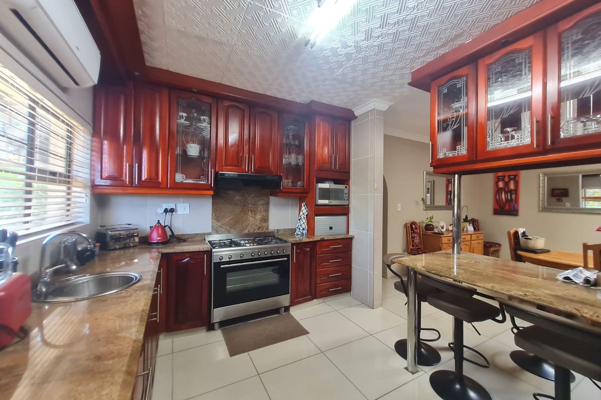 A functional kitchen featuring dark wood cabinetry, granite countertops, a built-in gas stove with extractor fan, and an integrated breakfast bar.