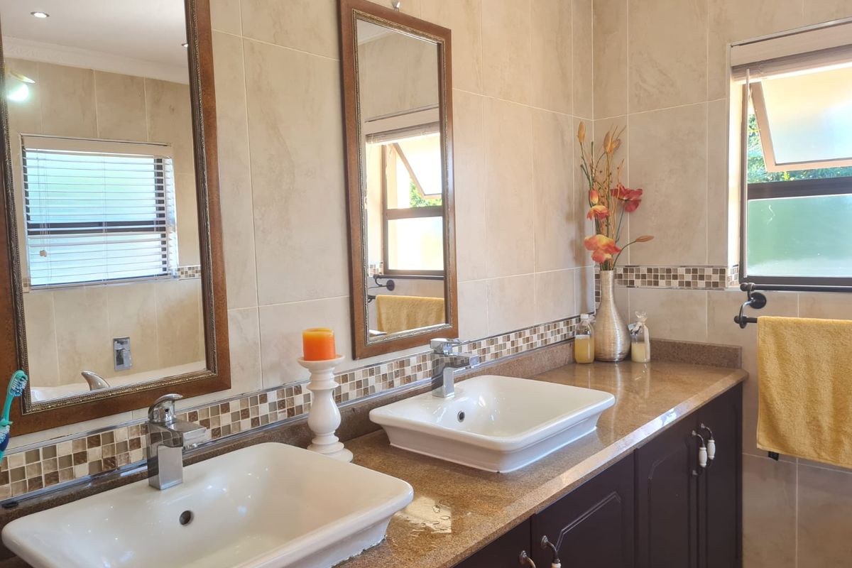 A well-maintained bathroom featuring a double vanity with granite countertops, vessel sinks, mosaic tile accents, and framed mirrors.
