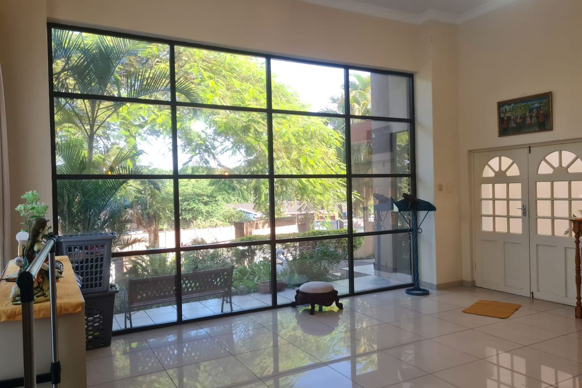 Spacious living area featuring large floor-to-ceiling grid-style windows that provide abundant natural light and views of the garden.