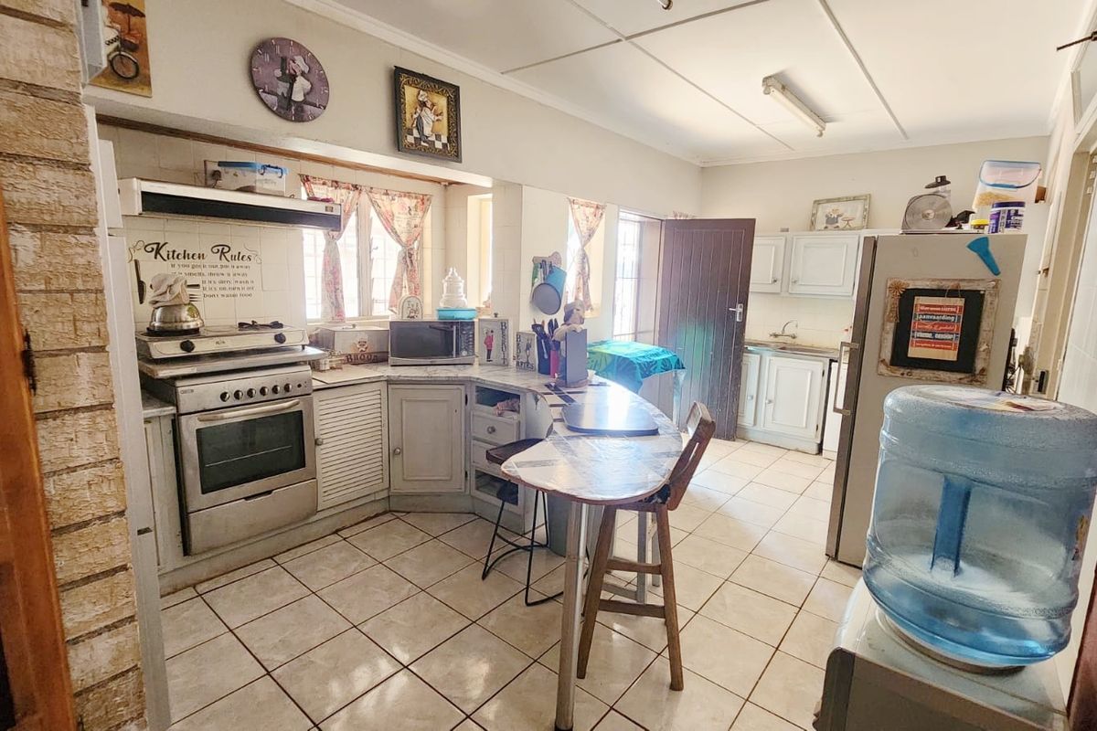 A functional kitchen featuring built-in cabinetry, a freestanding stove with extractor fan, tiled flooring, and a breakfast nook area.