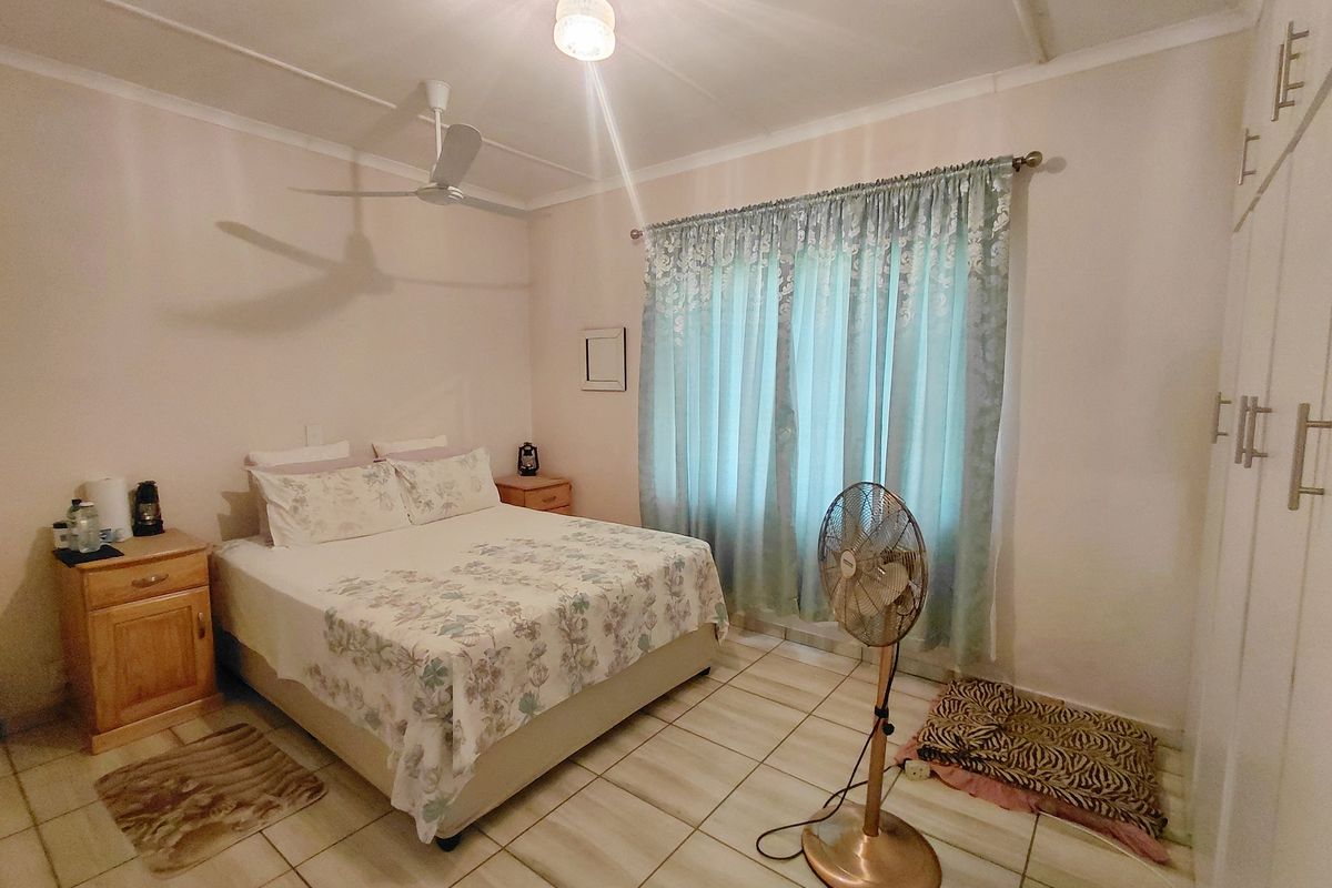 A functional bedroom featuring tiled flooring, a ceiling fan, and built-in wardrobe cabinetry.