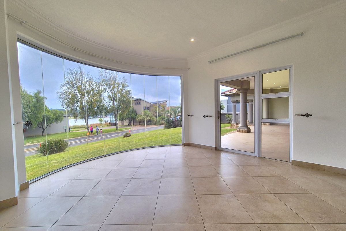Bright and spacious living area featuring large curved glass windows, tiled flooring, and direct access to an outdoor patio area.