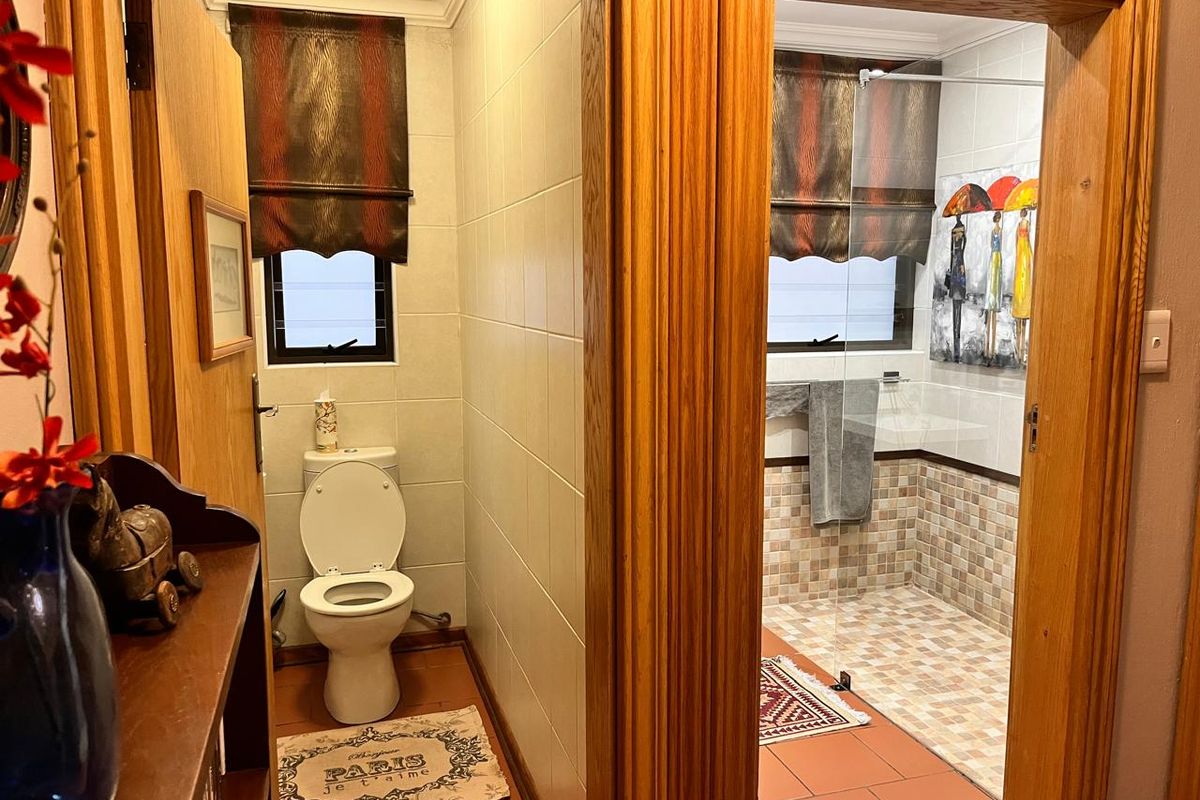A functional bathroom featuring a separate toilet area and a shower enclosure with tiled finishes and a glass screen.
