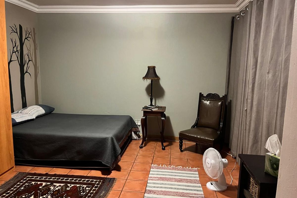 A bedroom featuring terracotta floor tiles, crown molding, and neutral wall paint.