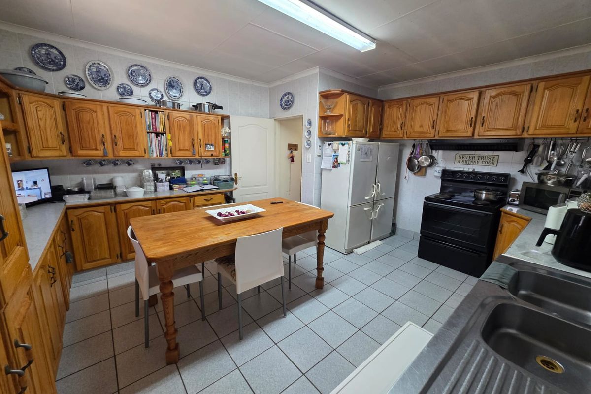 A functional kitchen featuring traditional timber cabinetry, tiled flooring, and a central dining area, offering a classic layout with ample storage space.