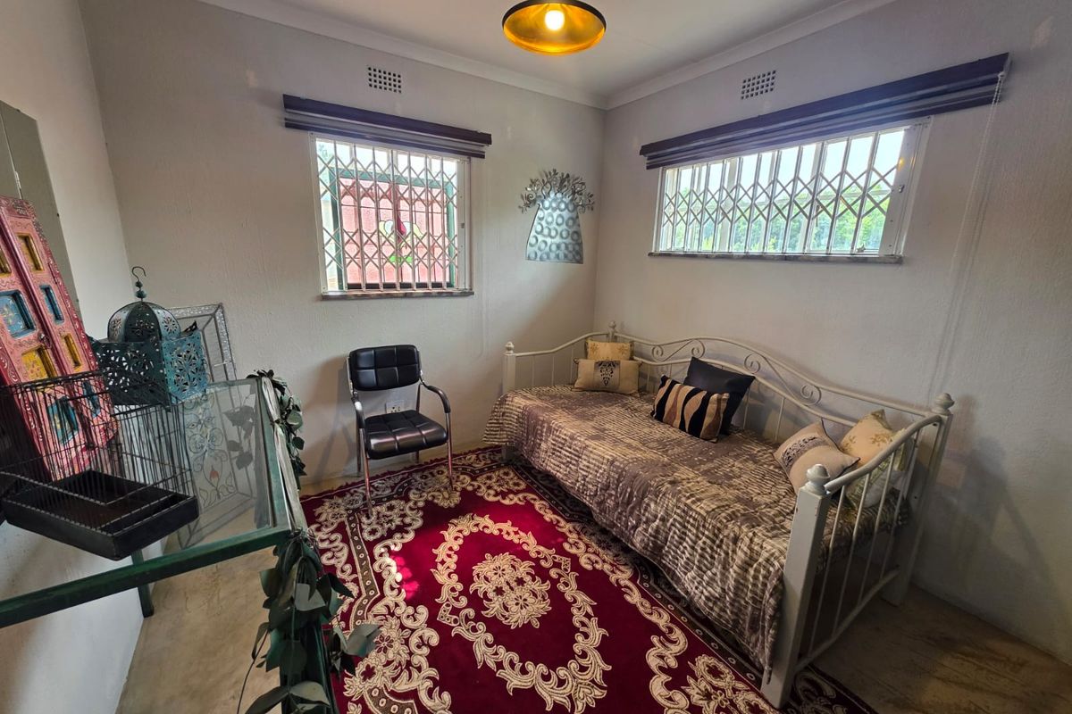 A bedroom featuring tiled flooring, security bars on windows, and a central pendant light fixture.