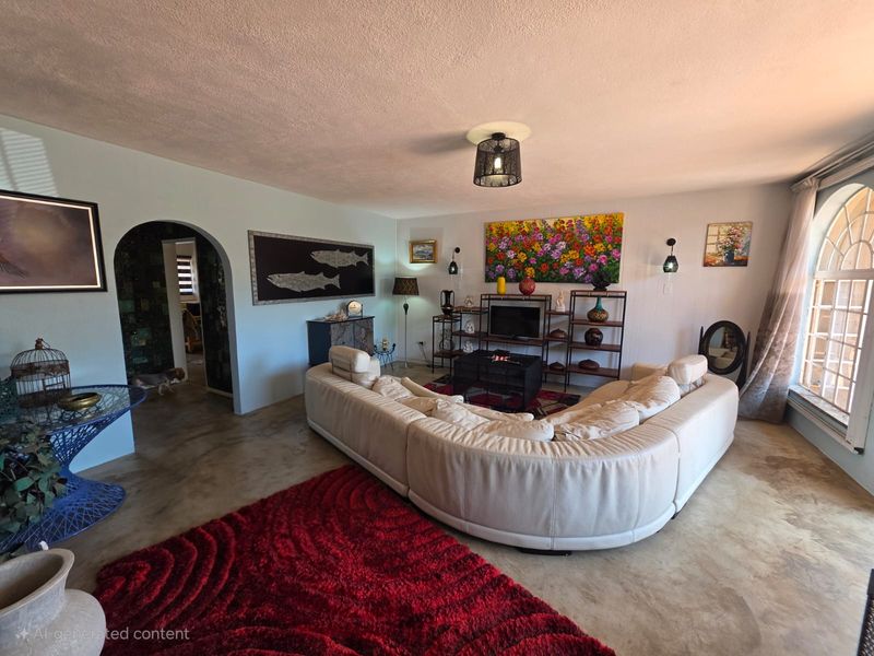 Spacious living room featuring an arched doorway, polished concrete flooring, and a large arched window allowing natural light.