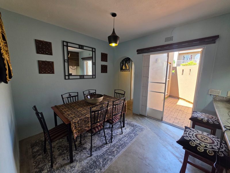 Dining area featuring concrete flooring, a pendant light, and a sliding glass door providing access to an outdoor patio space.