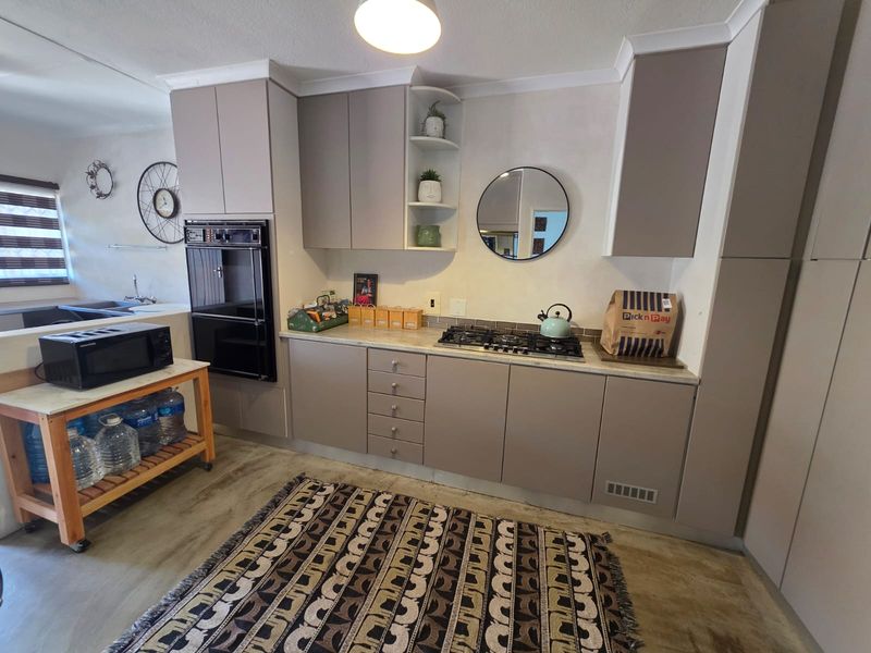 A functional kitchen featuring modern taupe cabinetry, a built-in double oven, gas hob, and tiled backsplash, offering a clean and practical workspace.