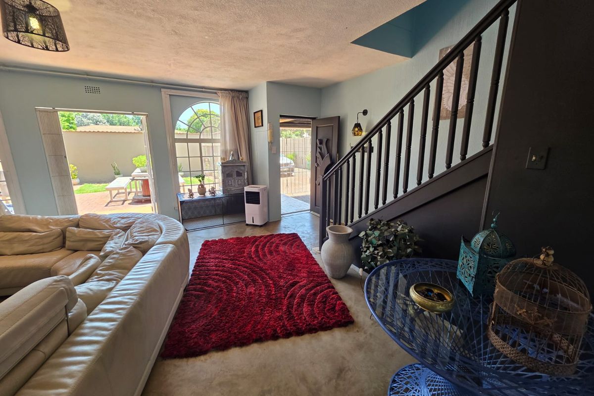 Spacious living area featuring a staircase with a wooden balustrade, an arched window, and direct access to the outdoor patio area.