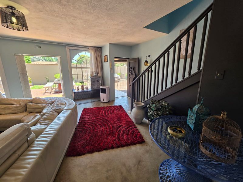 Spacious living area featuring a staircase with a wooden balustrade, an arched window, and direct access to the outdoor patio area.