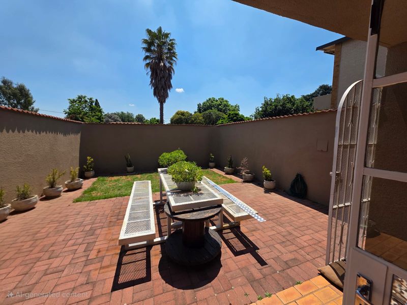 A private outdoor patio area featuring brick paving and enclosed by a perimeter boundary wall, providing a functional space for outdoor relaxation.