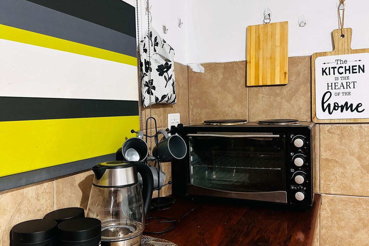 A compact kitchen corner featuring a wooden countertop, tiled backsplash, and built-in oven space.