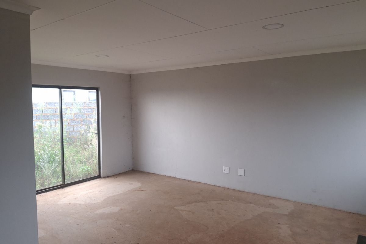 An empty, unfinished room featuring a sliding glass door, recessed ceiling lighting, and bare concrete flooring, ready for final finishes.