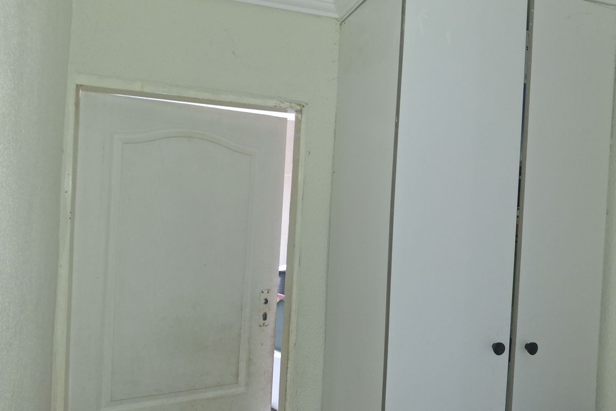 A bedroom interior featuring built-in white cabinetry and a standard interior door with visible wear on the finishes.