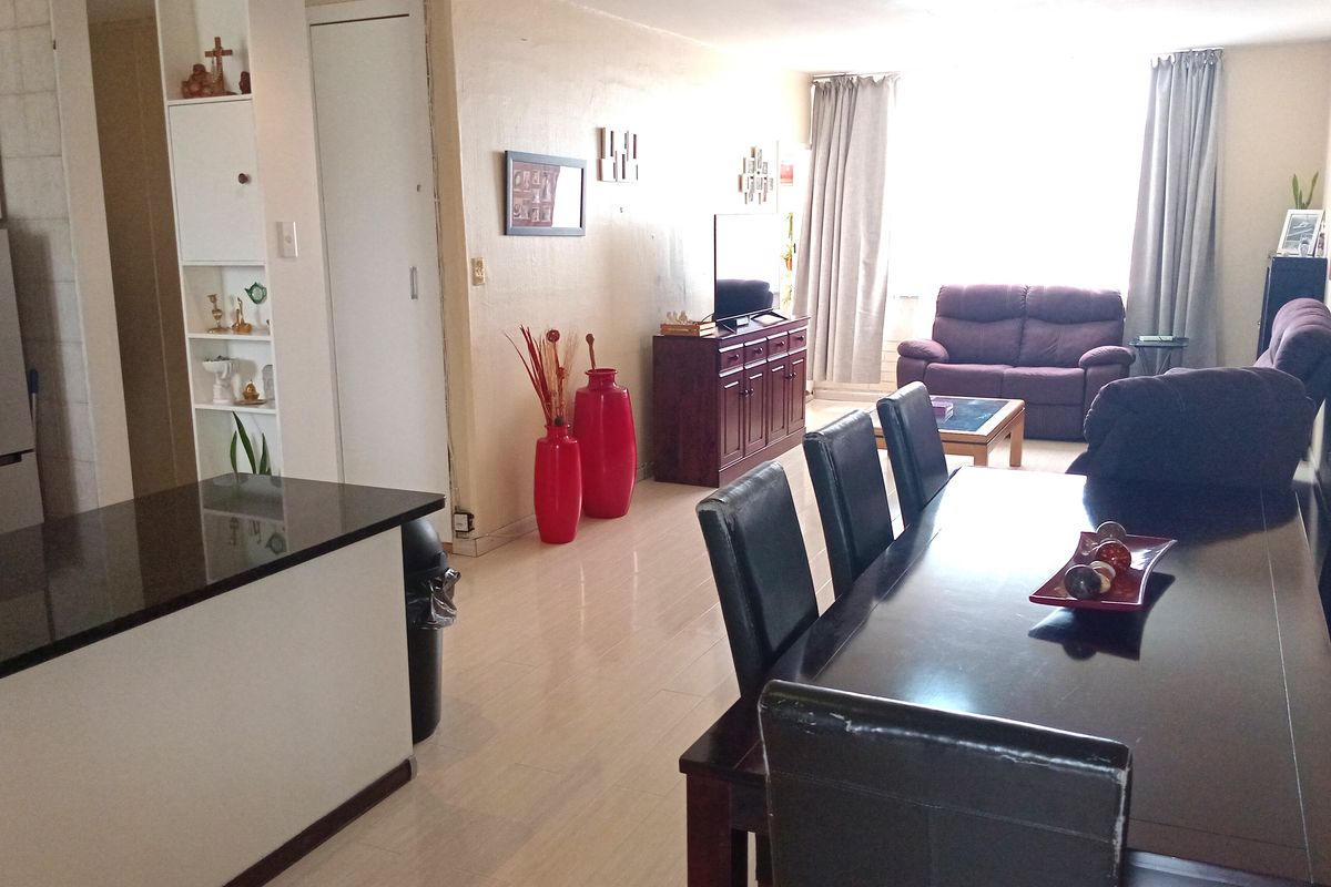 Open-plan living and dining area featuring a kitchen breakfast bar, tiled flooring, and natural light from the window.