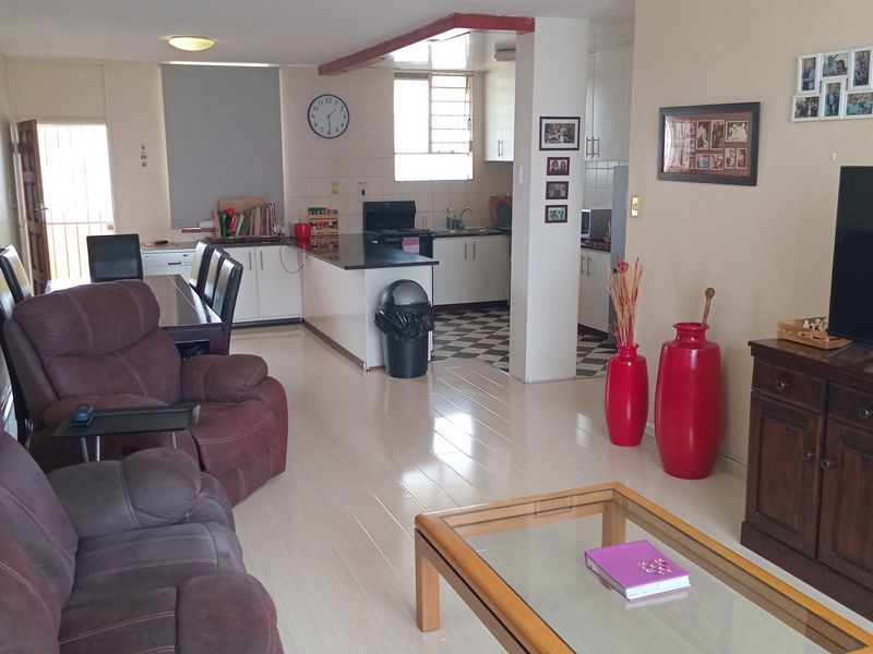 Open plan living and kitchen area featuring tiled flooring, built-in kitchen cabinetry, and a breakfast counter.
