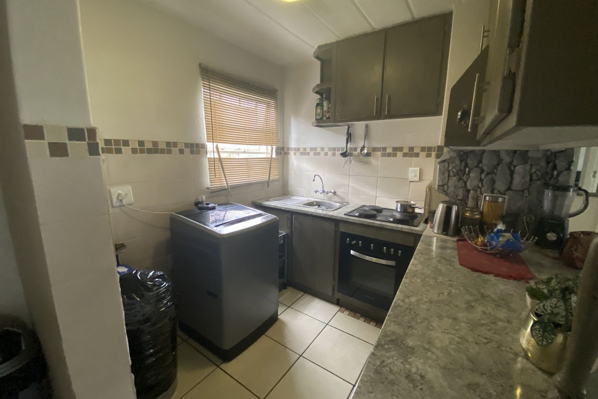 Compact kitchen featuring built-in cabinetry, electric hob, oven, and tiled backsplash with a functional layout for efficient meal preparation.