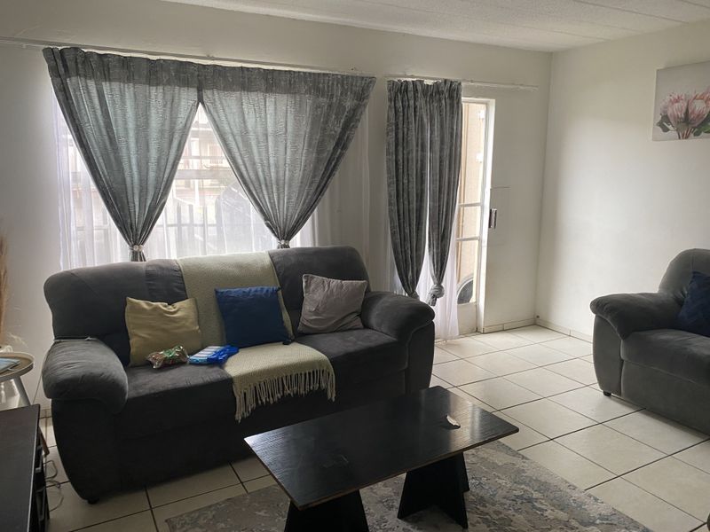 A living room featuring neutral tiled flooring and a sliding glass door providing access to the exterior.
