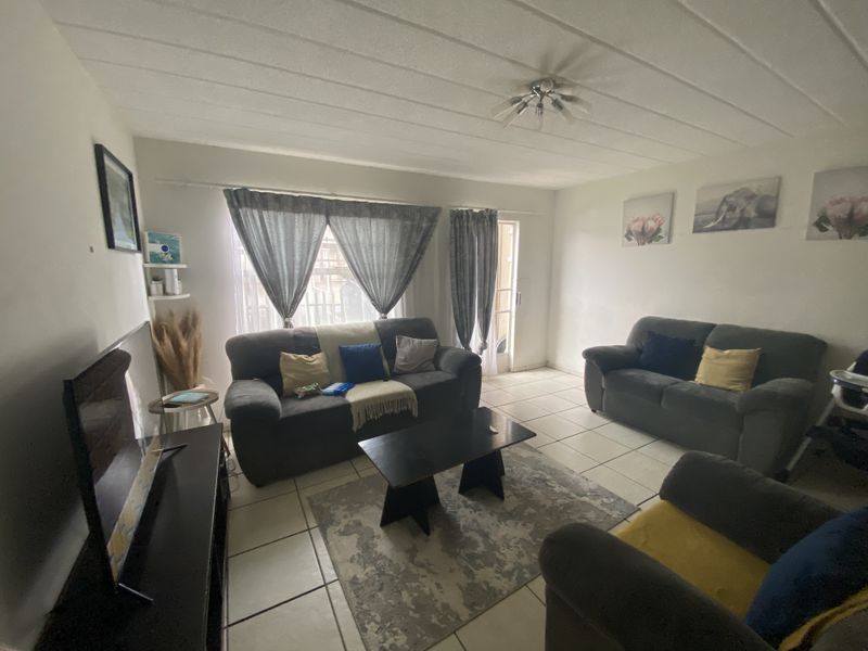 A functional living room featuring tiled flooring, a textured ceiling, and a sliding glass door providing access to the exterior.