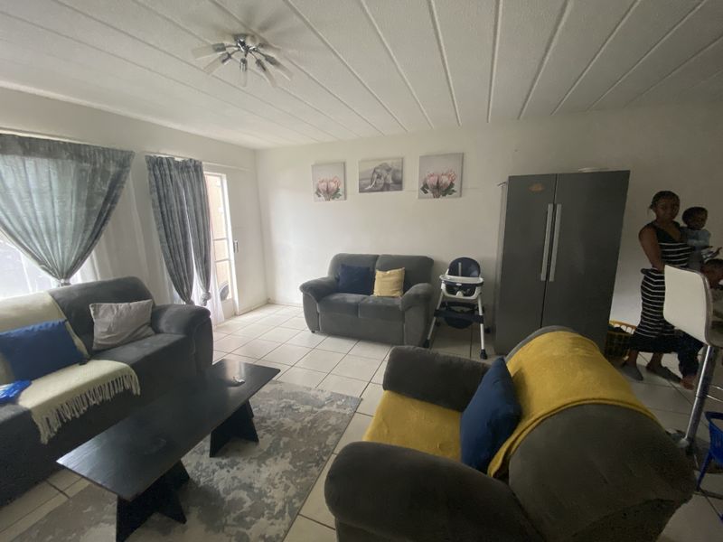 A living room area featuring tiled flooring and a sliding glass door providing access to the exterior.
