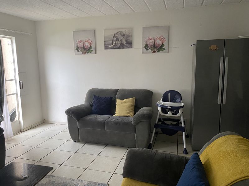 A living room area featuring neutral tiled flooring and a sliding glass door providing access to the exterior.