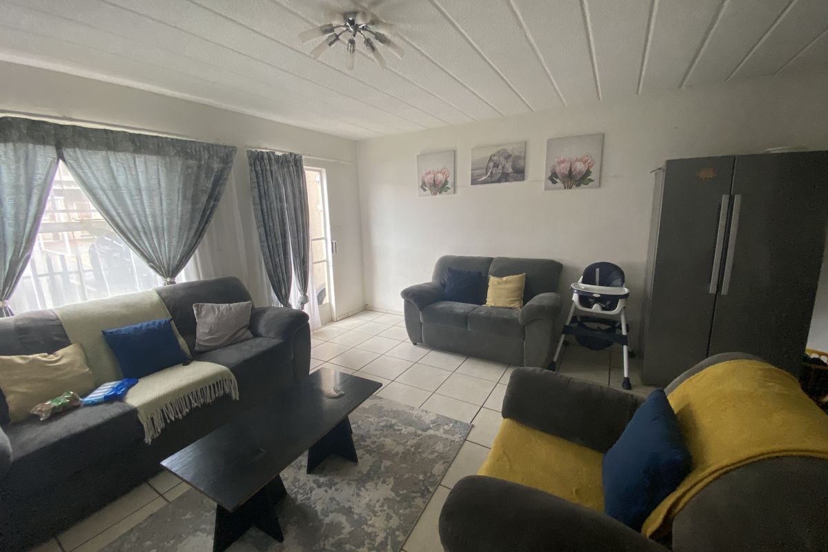 A living room featuring tiled flooring, a ceiling light fixture, and a sliding glass door providing access to the exterior.