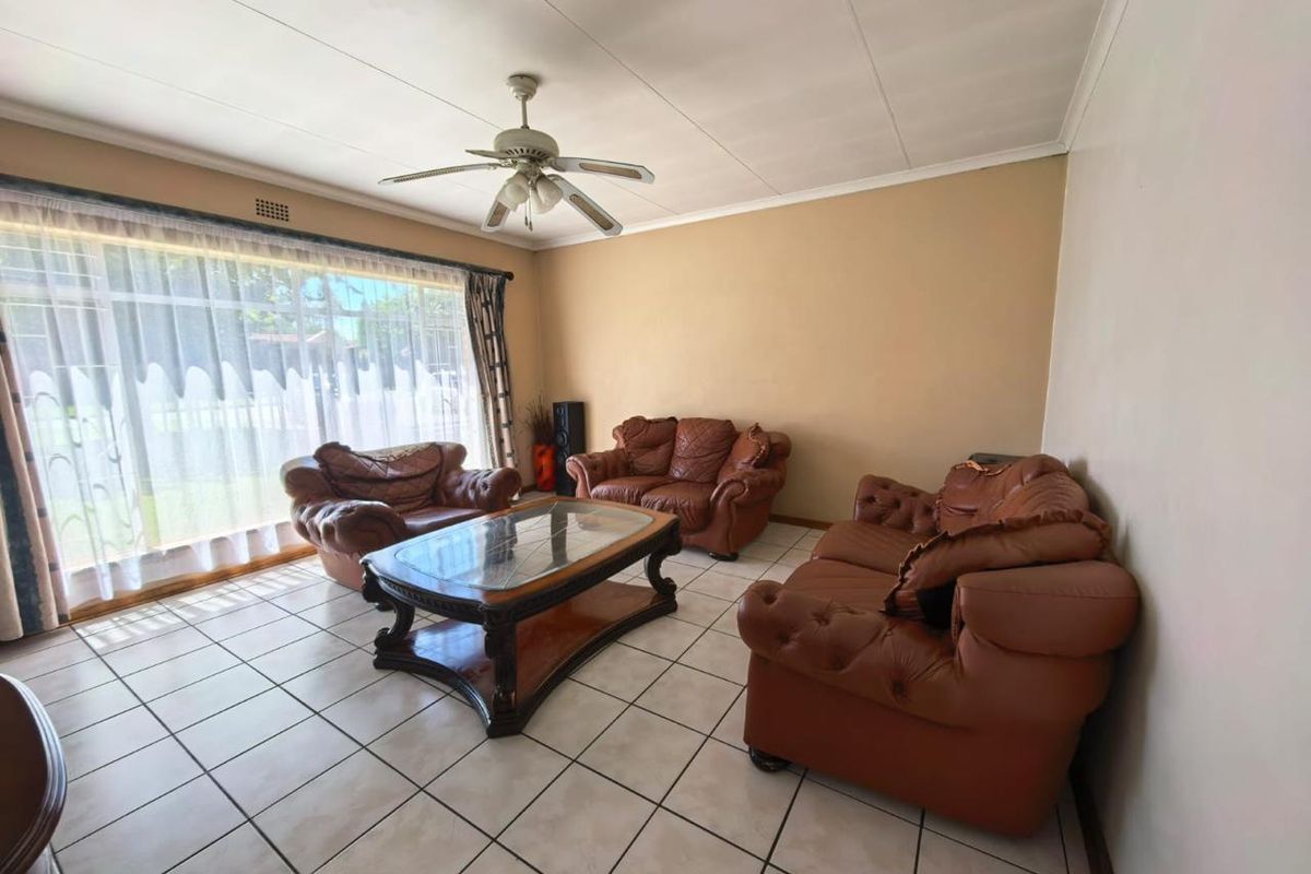 A spacious living room featuring large sliding glass doors, tiled flooring, and a ceiling fan, offering a bright and functional living space.