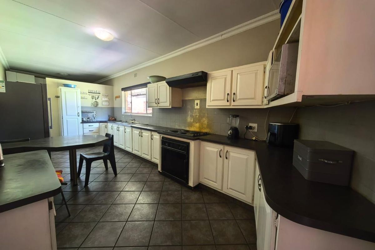 Spacious kitchen featuring white cabinetry, dark countertops, tiled flooring, and a built-in oven with extractor fan.