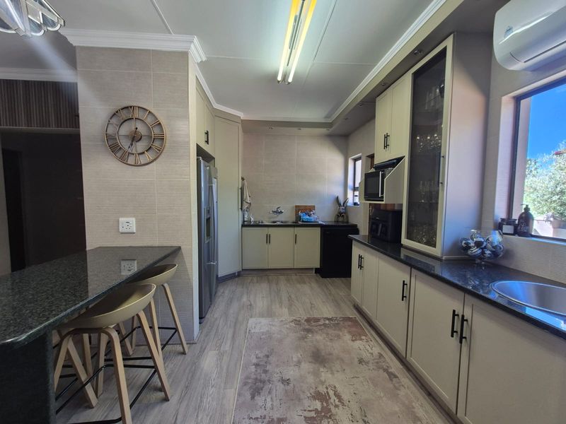 A well-maintained kitchen featuring granite countertops, ample built-in cabinetry, a breakfast bar, and a wall-mounted air conditioning unit.