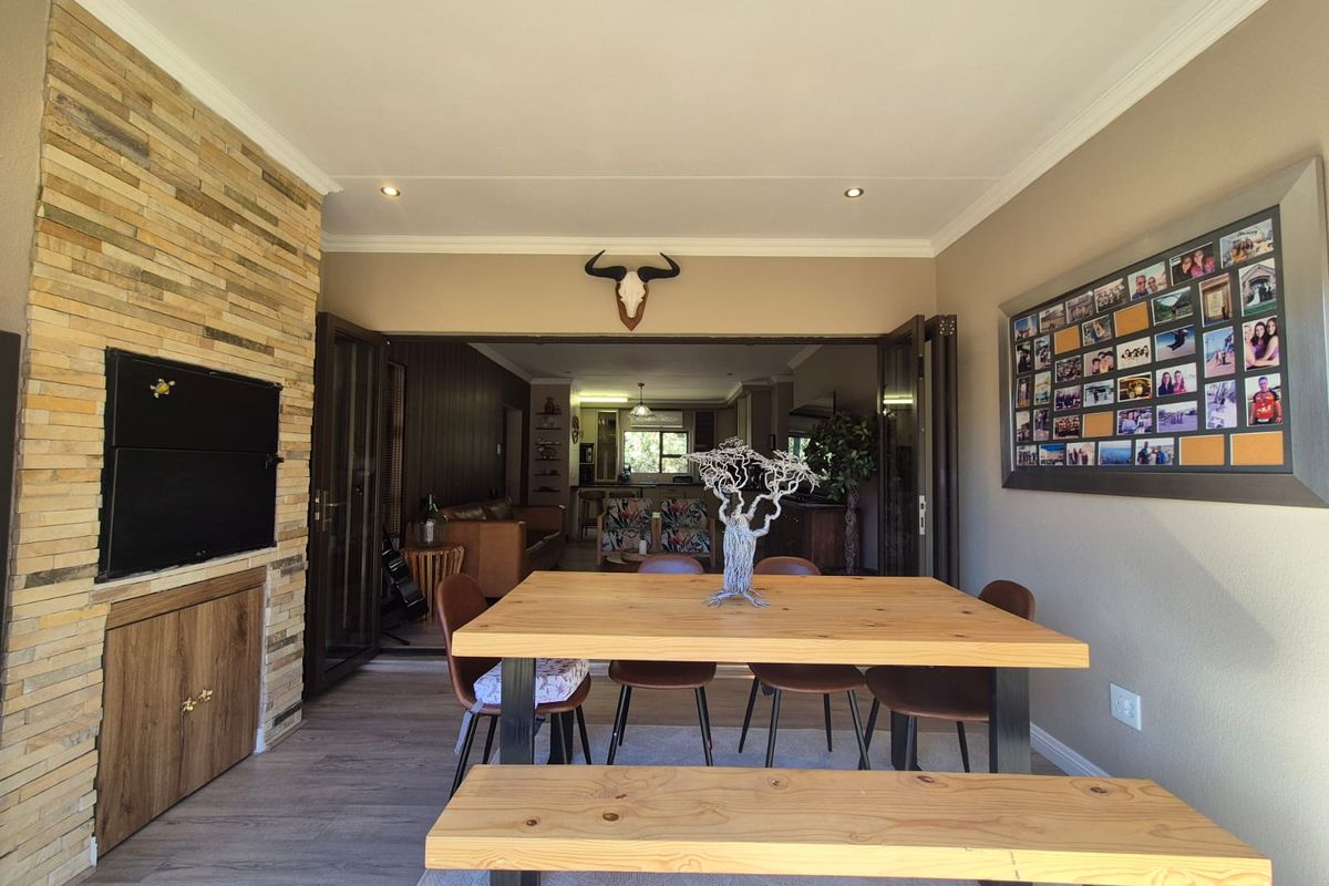 Spacious open-plan living and dining area featuring a stone-clad fireplace, modern laminate flooring, and large stacking doors leading to the interior living space.