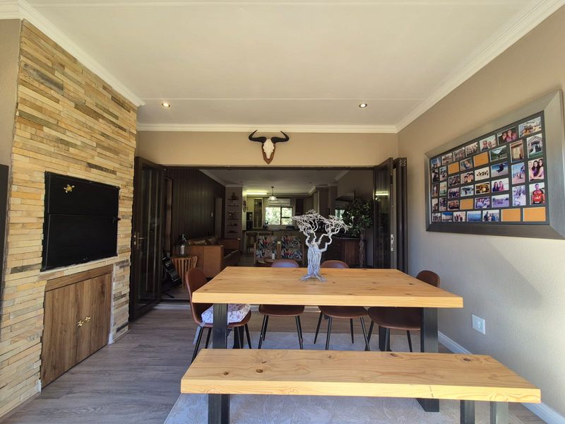 Spacious open-plan living and dining area featuring a stone-clad fireplace, modern laminate flooring, and large stacking doors leading to the interior living space.