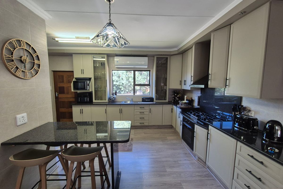 Modern kitchen featuring granite countertops, ample built-in cabinetry, gas hob, integrated oven, and a breakfast nook, finished with durable laminate flooring.