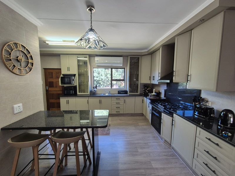 Modern kitchen featuring granite countertops, ample built-in cabinetry, gas hob, integrated oven, and a breakfast nook, finished with durable laminate flooring.