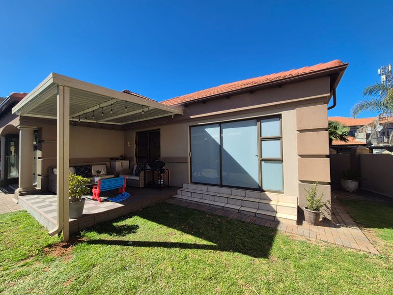 A well-maintained covered patio area featuring tiled flooring and direct access to the interior through a large sliding glass door.
