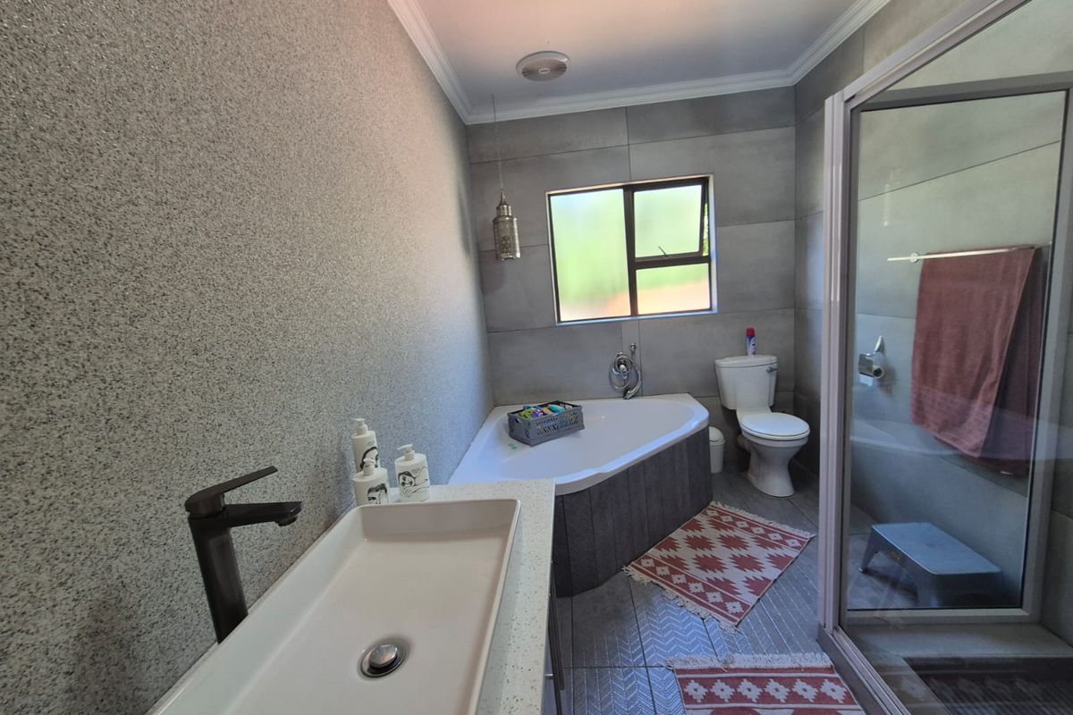 Modern bathroom featuring a corner bathtub, separate glass shower enclosure, vessel sink with contemporary faucet, and neutral tiled finishes.