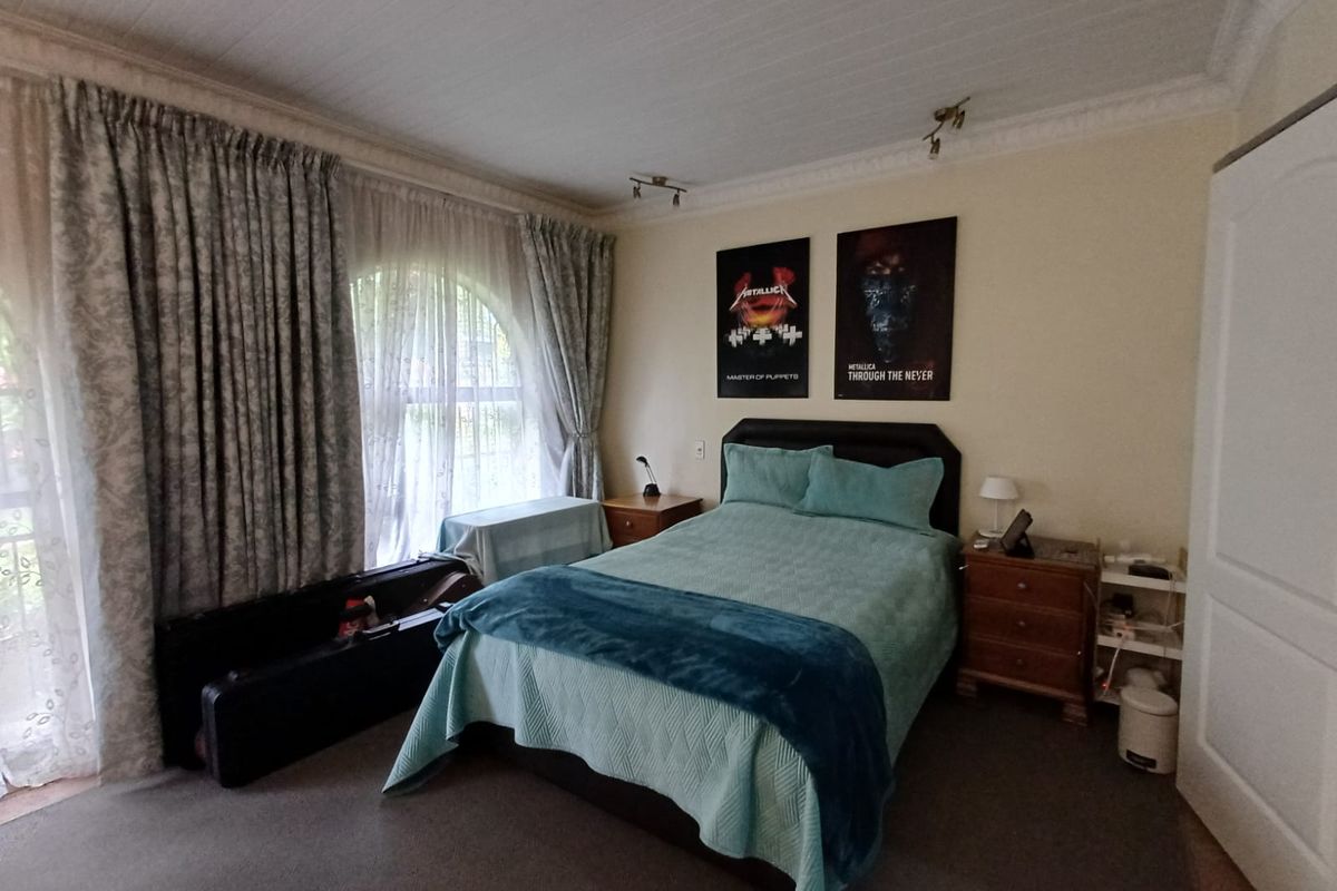 A spacious bedroom featuring an arched window, decorative ceiling cornicing, and a built-in wardrobe, offering a comfortable and functional living space.