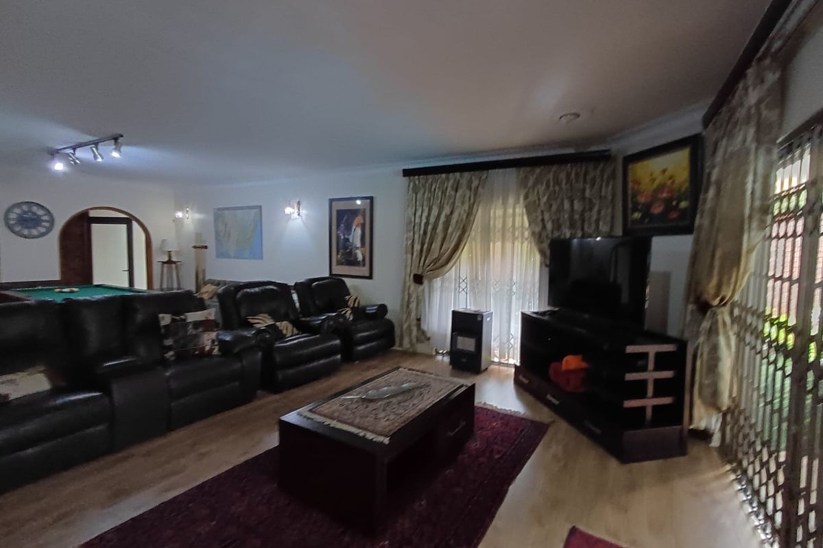 Spacious living room featuring laminate flooring, wall sconces, and a security gate, providing a comfortable area for relaxation and entertainment.