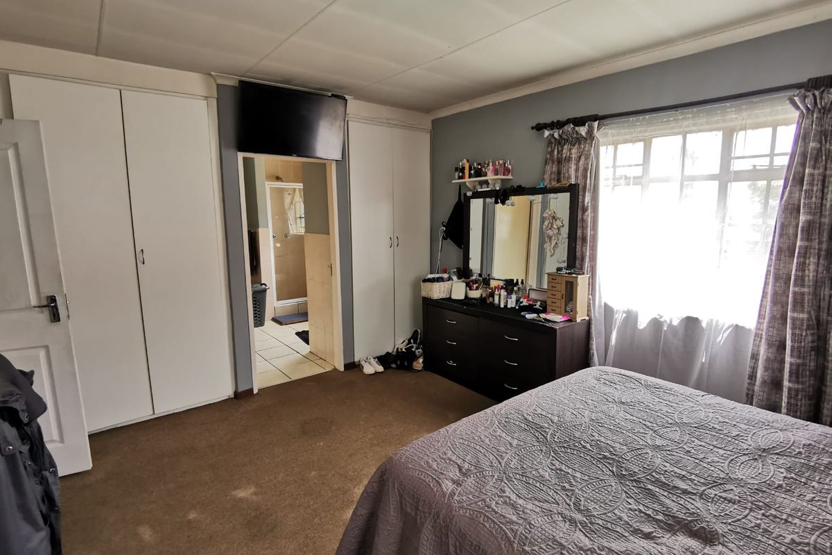 A bedroom featuring built-in cupboards, carpeted flooring, and an en-suite bathroom access point.