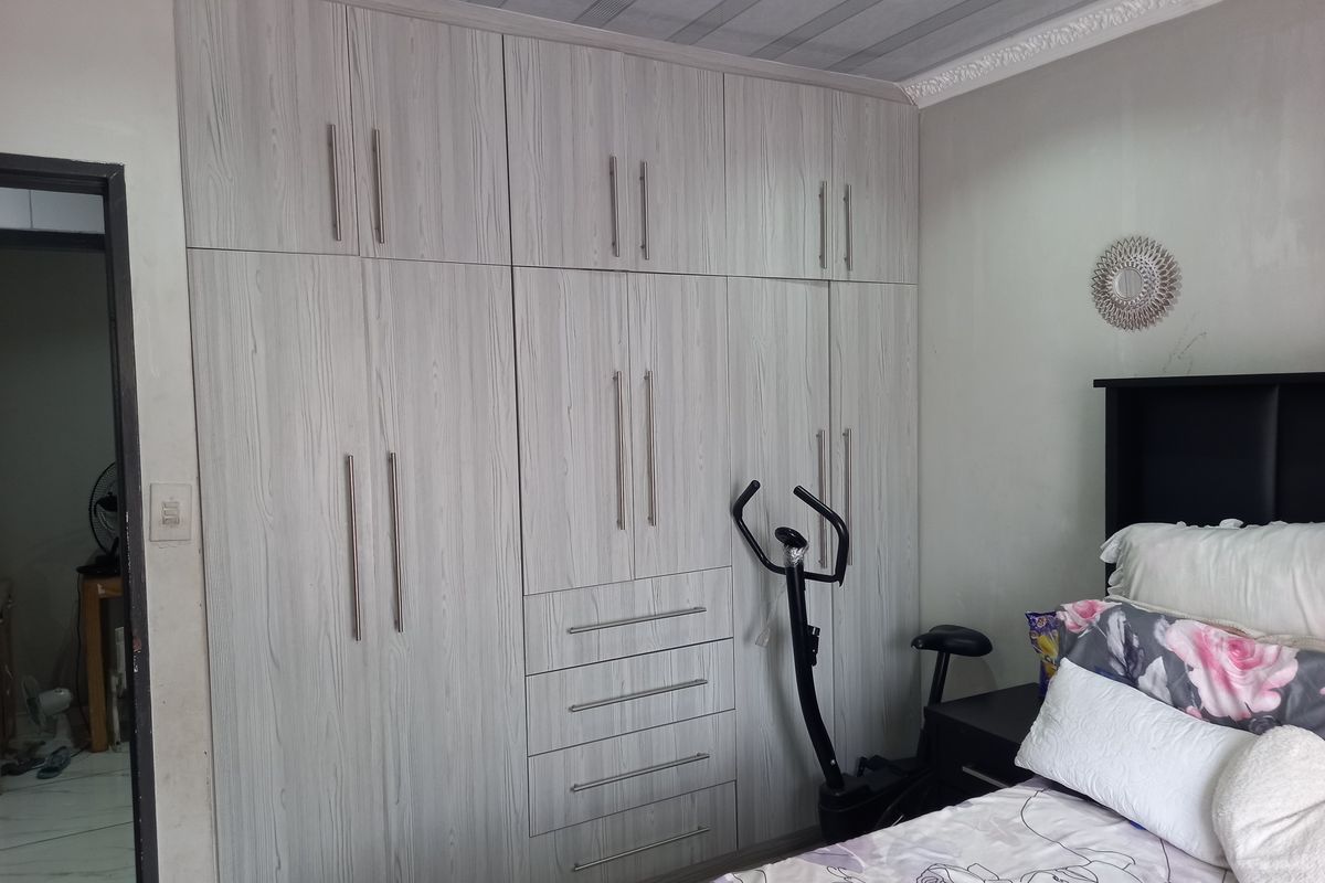 A bedroom featuring extensive floor-to-ceiling built-in cabinetry with a light wood-grain finish, providing ample integrated storage space.