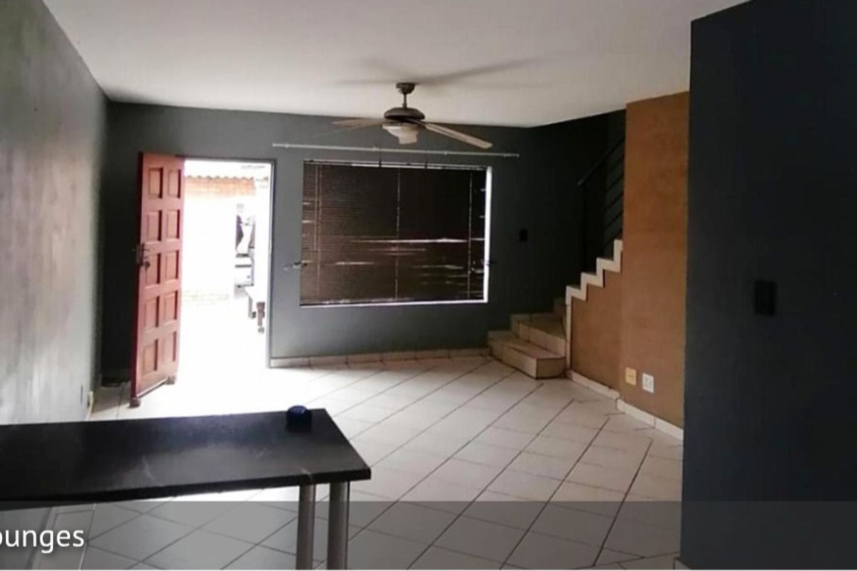 Open plan living area featuring tiled flooring, a ceiling fan, and staircase access to the upper level.