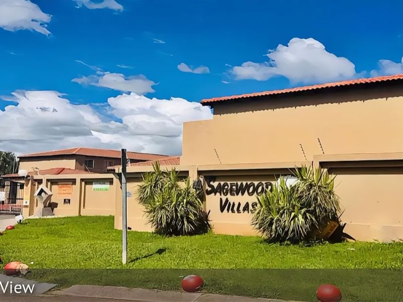 Front view of the Sagewood Villas townhouse complex, featuring a secure perimeter wall, electric fencing, and well-maintained landscaping.