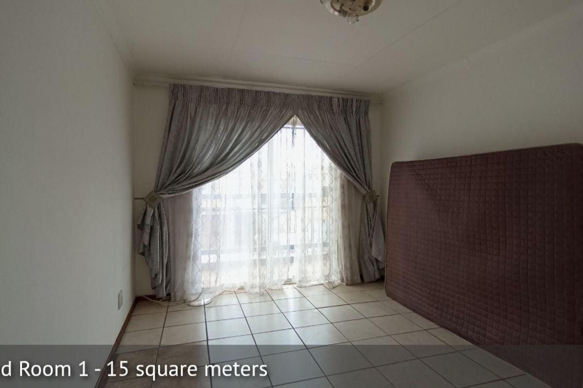 A bedroom featuring tiled flooring and a sliding glass door providing natural light.